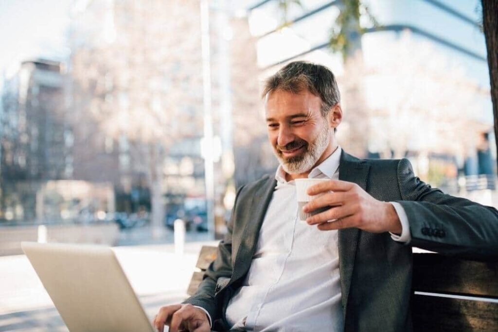 Mężczyzna pijący kawę i pracujący na laptopie