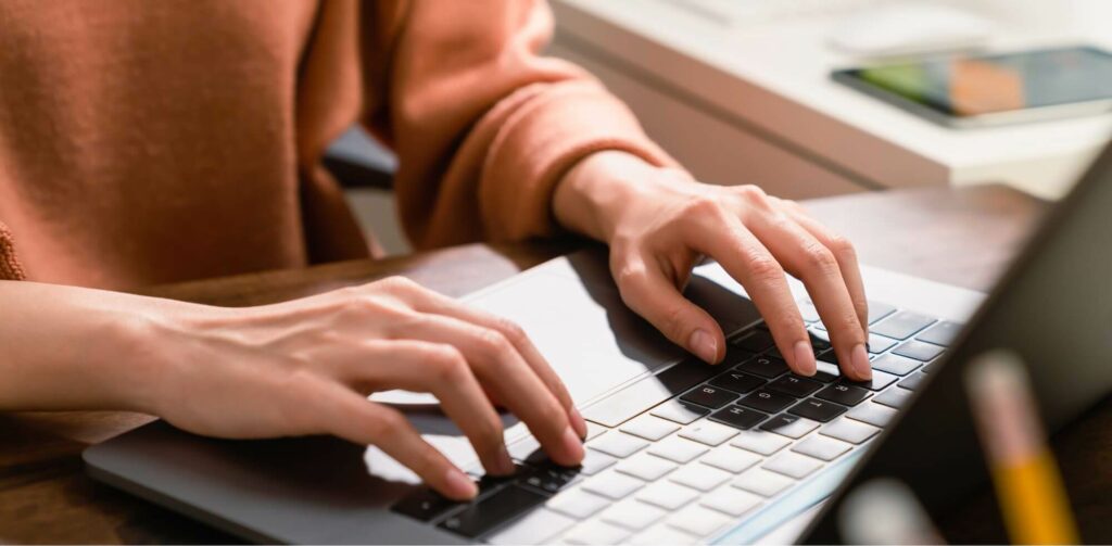 osoba pracująca na laptopie, zbliżenie na ręce i klawiaturę